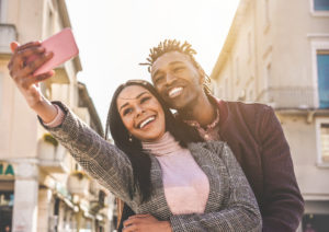 Latin couple taking selfie photo for social network story - Influencers people having fun with new trend technology - Love, fashion and relationship concept - Focus on faces